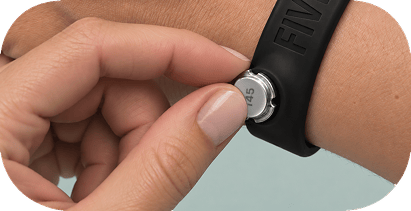 A woman presses a steel pebble into the FIVE.FIT band on her wrist.