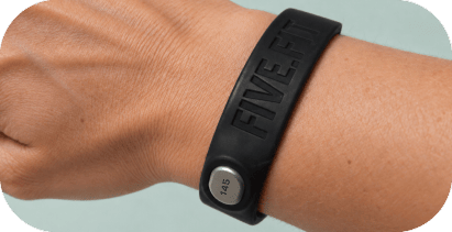 A steel pebble sits raised above the FIVE.FIT band on a woman's wrist.